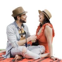 Young couple of lovers drinking cocktails doing picnic at city park during coronavirus outbreak - Focus on faces